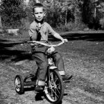 Mid-1960s. Paul on tricycle in driveway of house in Luck, Wisconsin.