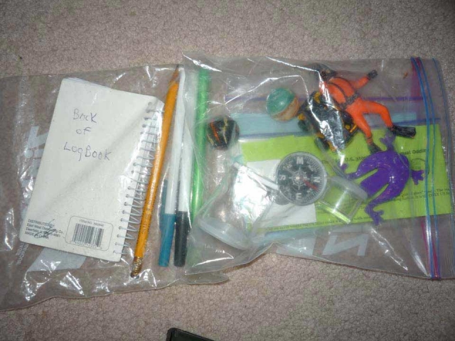 Good example of cache content. Trinkets for geocache finders to trade with, a log book to prove you found the geocache.