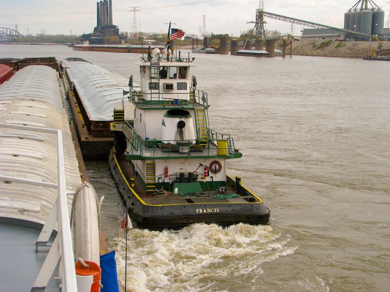 Auxilliary boat moves each barge in place to get cabled to tow