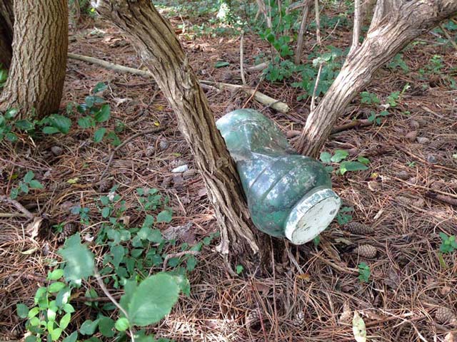 Example of a poor geocache container and placement. Plastic will crack. Not hidden very well. A geocache should not look like junk.